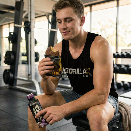 Man in a gym holding a supplement bottle and snack bar